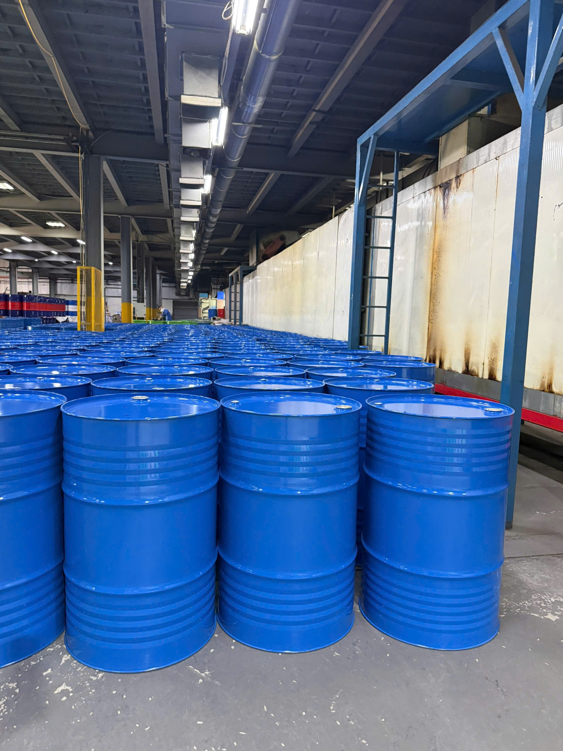 Dãy phuy sắt xanh dương mới nắp kín trong nhà xưởng công nghiệp