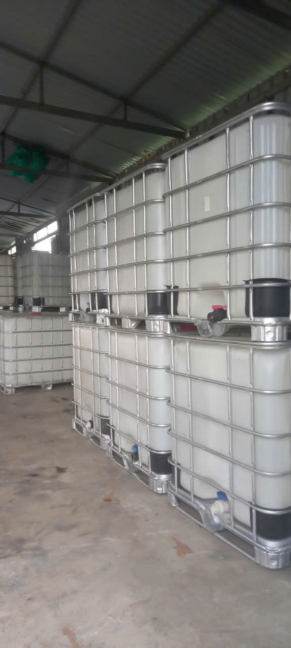 Dãy bồn IBC trắng khung thép xếp hai tầng trong nhà kho mái tôn