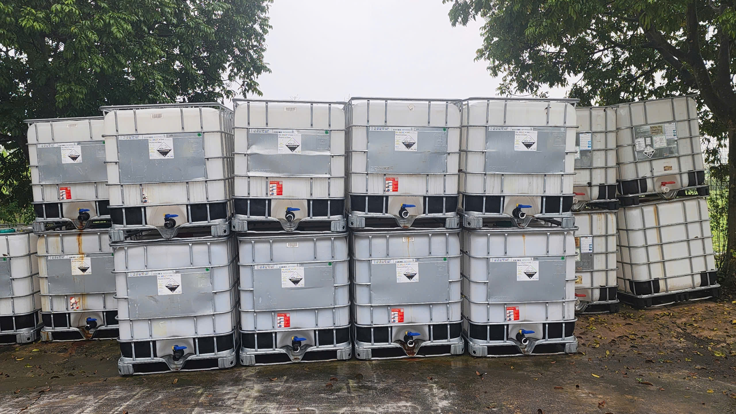Bãi tank IBC 1000L cũ xếp hai tầng ngoài trời, còn nhãn hóa chất của lần chứa trước