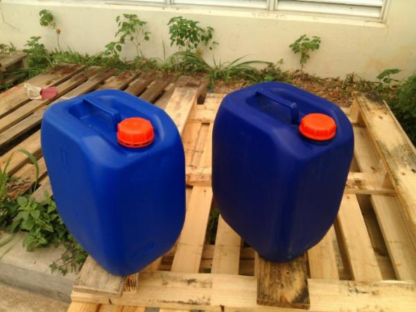 Hai vỏ can nhựa màu xanh dương, nắp cam, đặt trên pallet gỗ, có quai xách phía trên