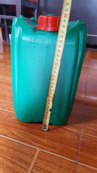 Can nhựa xanh lá nắp vặn đỏ đặt trên sàn gỗ cạnh thước dây