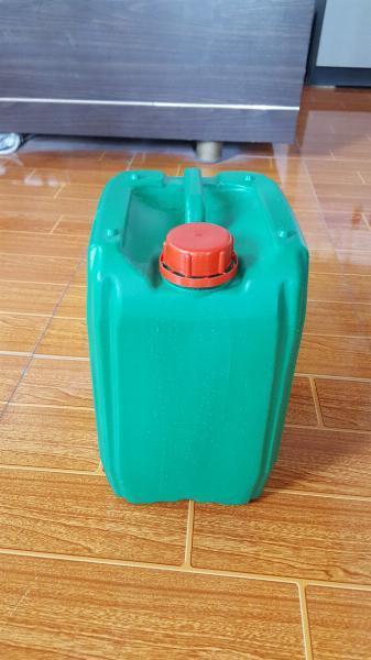 Can nhựa xanh lá nắp đỏ cỡ trung đặt trên sàn gỗ trước tủ gỗ