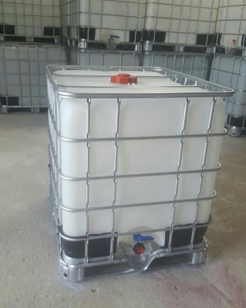 Tank IBC 1000 lít thân trắng đục trong khung sắt, nắp đỏ phía trên và van xả xanh ở đáy