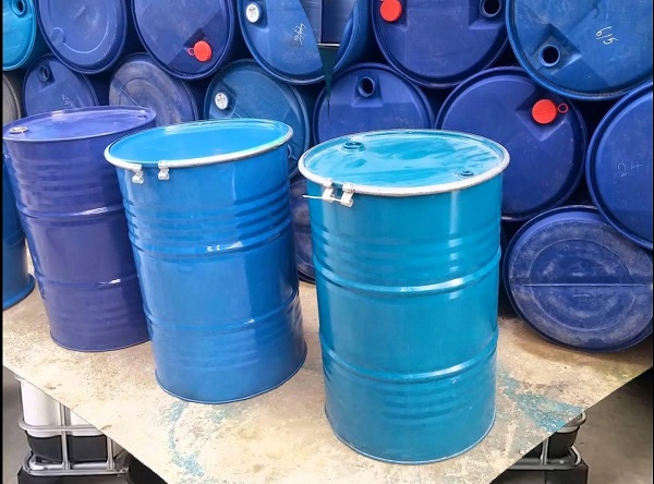 Phuy sắt xanh dương nắp mở có đai kẹp đặt trước chồng phuy nhựa