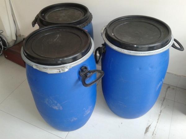 Hai phuy nhựa xanh dương nắp đen đai kẽm có quai xách, đặt cạnh tường