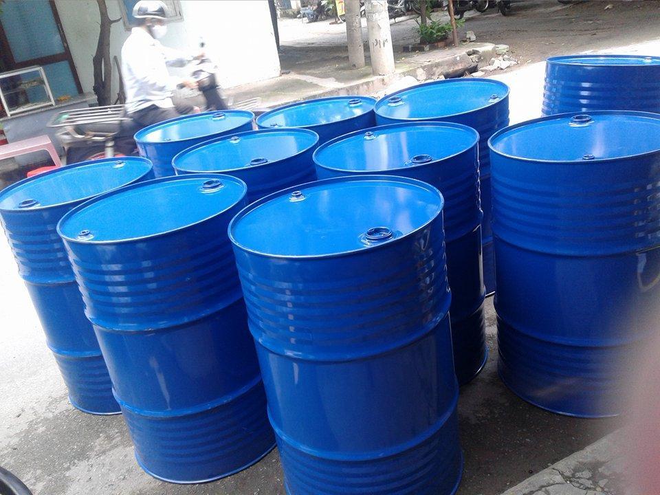 Thùng phi sắt sơn xanh dương có nhiều gân sóng quanh thân, nắp kín hai lỗ, xếp đứng trên vỉa hè